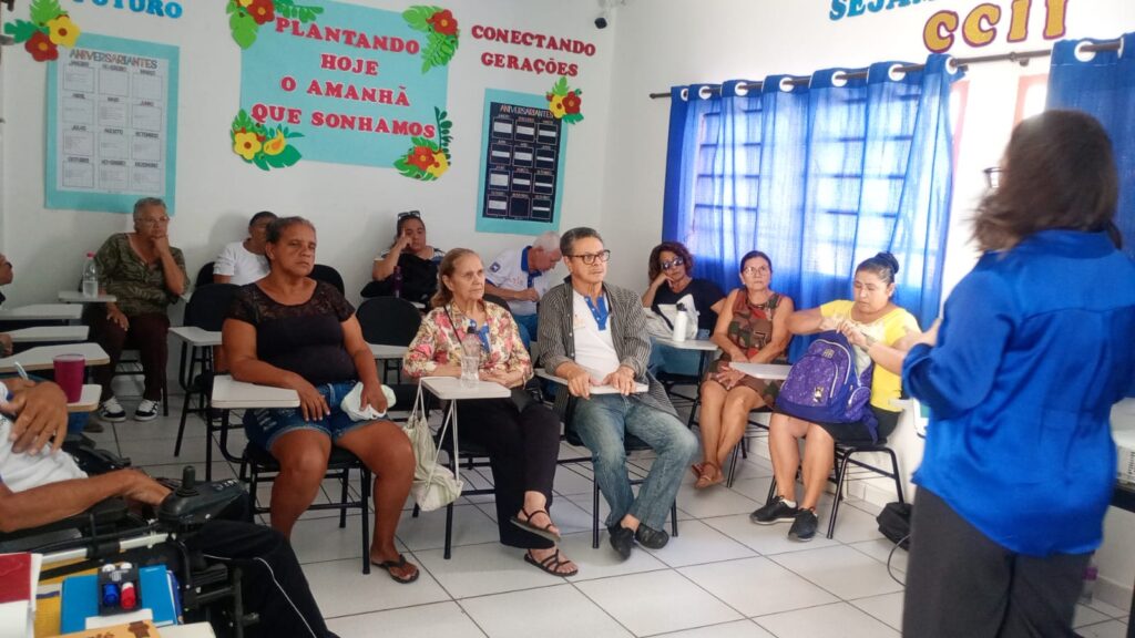 Participantes sentados em roda ouvem a advogada voluntária na sala do CCII